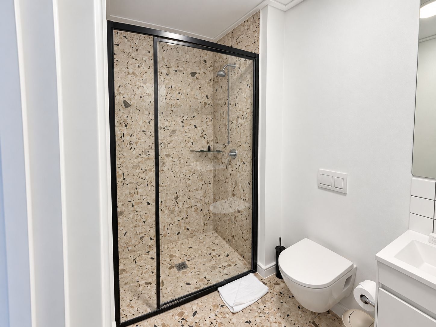 Un baño con ducha de vidrio, inodoro blanco y lavamanos.
