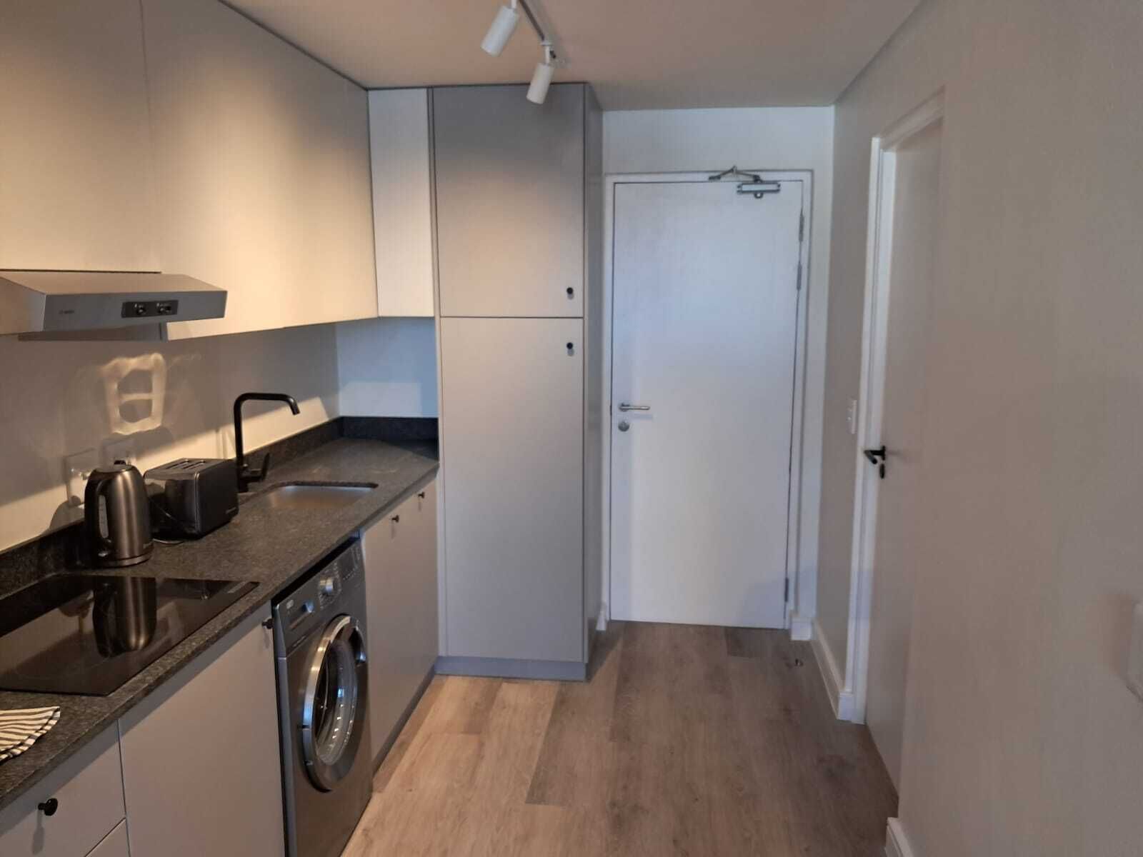 Eine kleine Küche mit Waschmaschine, Wasserkocher und Toaster.