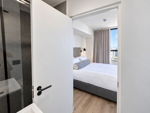 A modern hotel room with a bed, a bedside lamp, and a view of the city. - Maritime Place (Cape Town)