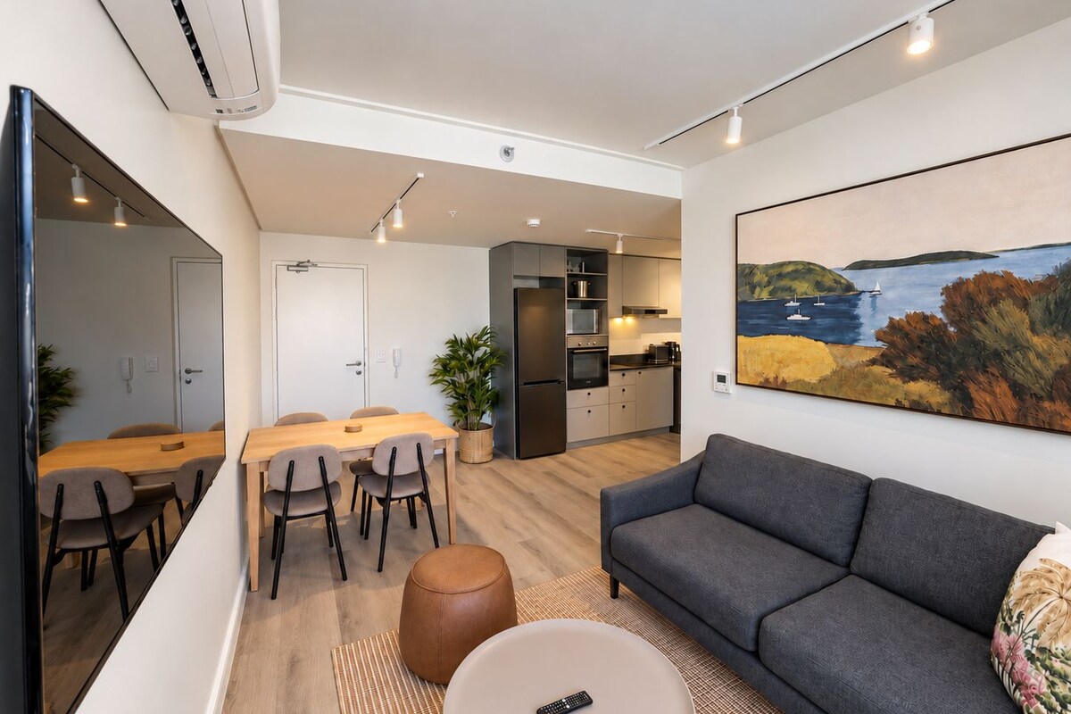 A modern living space with a dining area, kitchen, and a sofa.