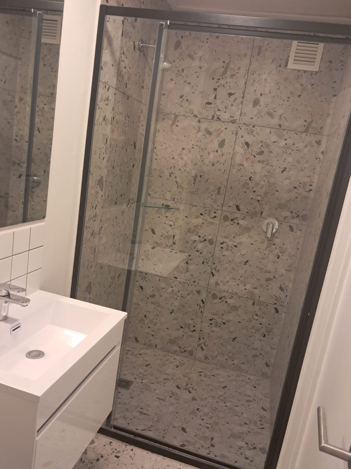 Un baño con cabina de ducha, lavamanos y espejo.