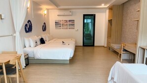 Une chambre d’hôtel avec un lit, un bureau et une chaise. Une porte donne sur l’extérieur.
