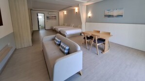 Une chambre d’hôtel avec un canapé, une table à manger avec des chaises, un lit et un tableau au mur.