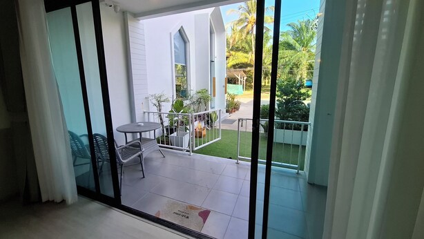 Une chambre moderne dotée d’une grande porte-fenêtre coulissante qui donne sur un espace extérieur aménagé avec une petite table et des chaises, un foyer et une pelouse bien entretenue.