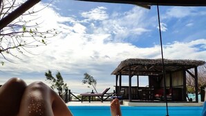 A beachside view with a pool, lounge chairs, and a thatched-roof structure. - Les Paillottes de Babaomby (Antsiranana)