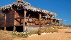 A wooden building with thatched roofs, situated on a sandy terrain. - Les Paillottes de Babaomby (Antsiranana)