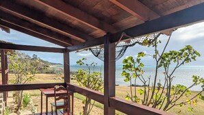 A wooden deck with a bench, a table, and a view of the beach and ocean. - Les Paillottes de Babaomby (Antsiranana)