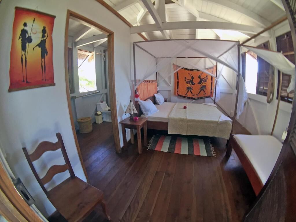 Una habitación con cama, una silla, una mesita y una ventana.