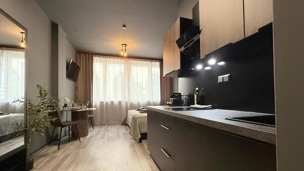 Uma cozinha moderna com área de refeições, piso de madeira e uma grande janela com cortinas.