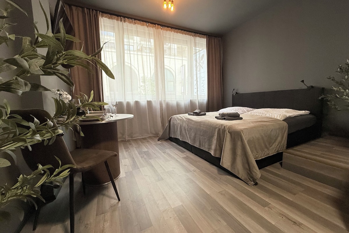 Un dormitorio con cama, un escritorio con silla, una planta en maceta y una ventana con cortinas.