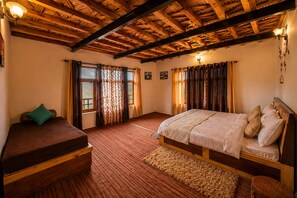 A room with a bed, a sofa, a rug, and a wooden ceiling.