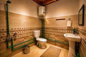 A bathroom with a toilet, sink, shower, and a water heater.