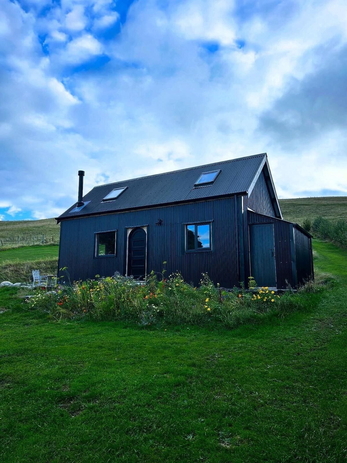 A single-story house with a dark exterior, a chimney, and a sloped roof.