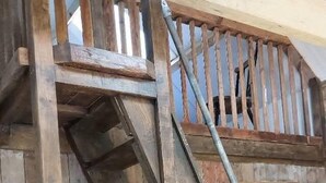 A wooden staircase with a metal handrail, leading to a lofted area with a wooden railing. - Barn Sleeps 4 With Enclosed Garden (Mold)