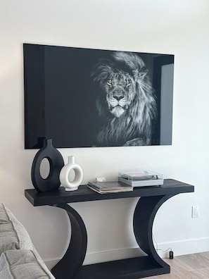 A modern living room with a black console table, a framed picture of a lion, and a vase. - Newly Built Modern Vacation Home 4 BR/3 BA Your Own Heated Pool, Lanai on Canal (Cape Coral)