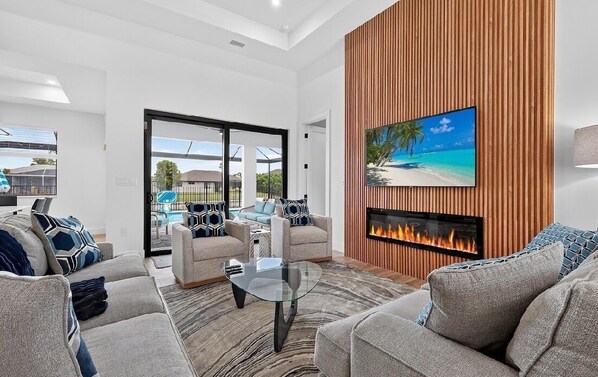 A modern living room with a fireplace, comfortable seating, and a large window.