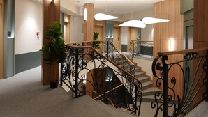 A modern interior with a staircase, wooden paneling, and a potted plant. - Hotel Botika (Kraljevo)