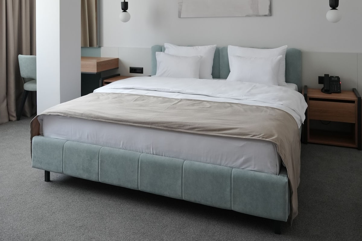 Una habitación de hotel moderna con una cama grande, mesitas de noche, un escritorio y una silla.