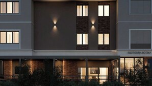 A modern building with a curved facade, multiple windows, and a sign reading 'RESTORAN BOTIKA'. - Hotel Botika (Kraljevo)