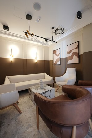 Una sala de estar moderna con sofá, sillas, una mesa de centro e iluminación en la pared.