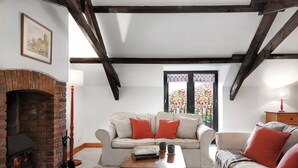 A cozy living room with a fireplace, a sofa set, a coffee table, and a window with a view. - Ivy Cottage, idyllic coastal retreat with sea views (Bideford)