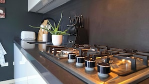 A modern kitchen with a stainless steel range, a potted plant, and a knife block. - Serene apartment with AC in vibrant Santa Cruz (Santa Cruz)