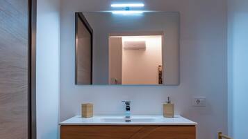 A modern bathroom with a wooden vanity, a large mirror, and a light fixture above the mirror.