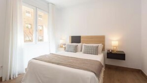 Ein Schlafzimmer mit einem Bett, Nachttischen und einem Fenster.