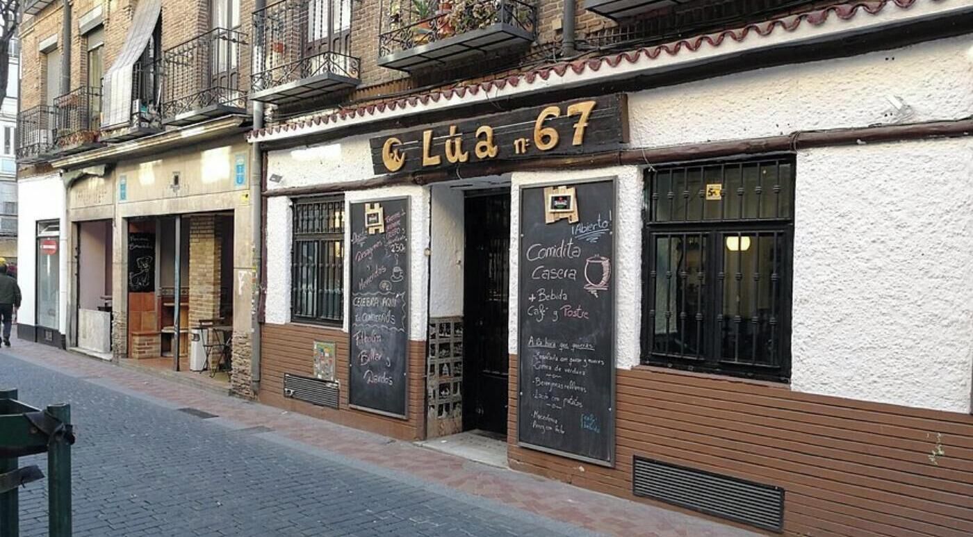 A street-side café with a chalkboard menu, wooden shutters, and a visible entrance.