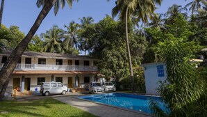 A two-story building with a swimming pool, surrounded by palm trees and greenery. - Awas Beach Stays By Glitz (Awas)
