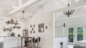 Een ruime keuken met houten balken, een eethoek met tafel en stoelen, en uitzicht op een balkon met een deur.