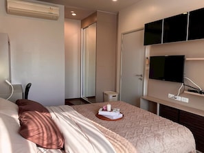 A hotel room with a bed, a television mounted on the wall, a door, and a small table with a basket. - Modern & Cozy Nest 3 Mins to BTS Saphan Khwai (Bangkok)
