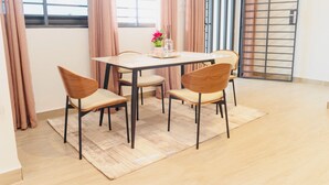 A dining area with a table and chairs, a window with curtains, and a view of the outside. - Cozy 1-bedroom apartment in serene Calavi with AC (calavi)