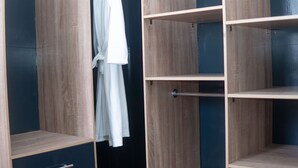 A wooden wardrobe with multiple shelves and a hanging robe. - Cozy 1-bedroom apartment in serene Calavi with AC (calavi)