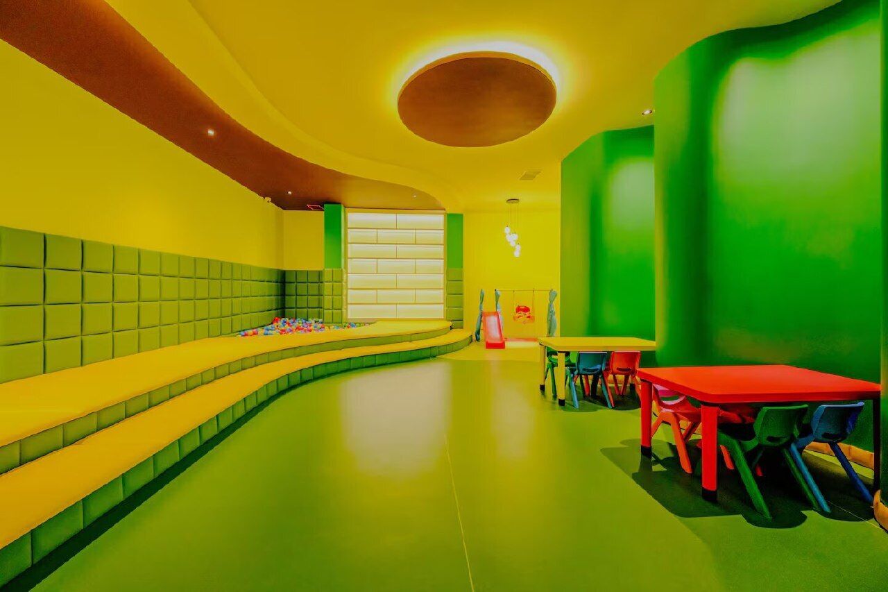 A brightly colored room with a curved bench, tables, and chairs.