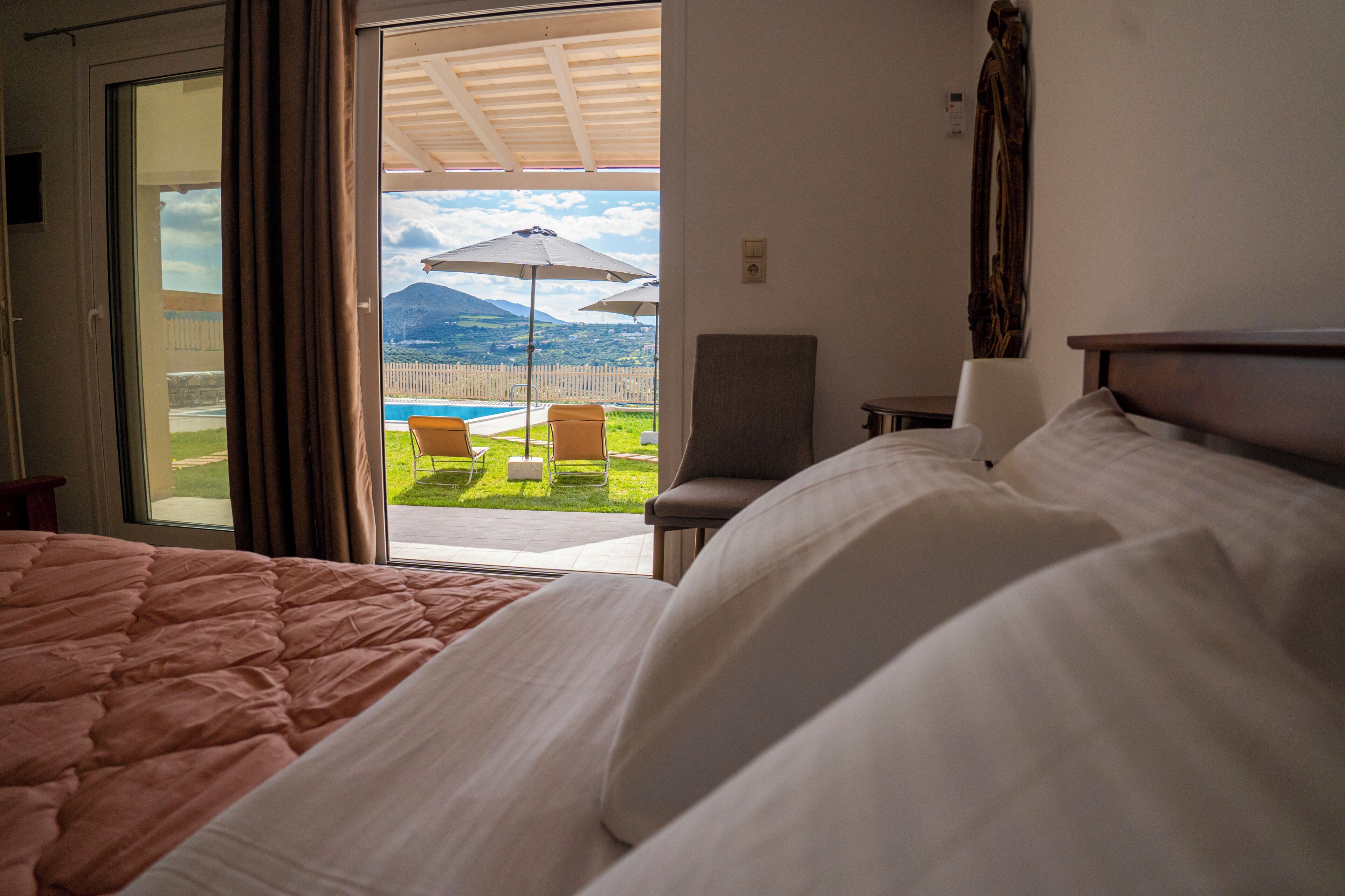 Habitación de hotel con cama, una silla y vistas a una piscina y montañas.