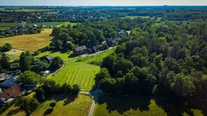 An aerial view of a residential area with houses, green fields, and a river. - Holiday Apartment “Im Grünen” with Balcony and Wi-Fi (Korschenbroich)