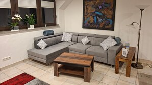 A modern living room with a grey sectional sofa, a wooden coffee table, a floor lamp, and a painting on the wall.