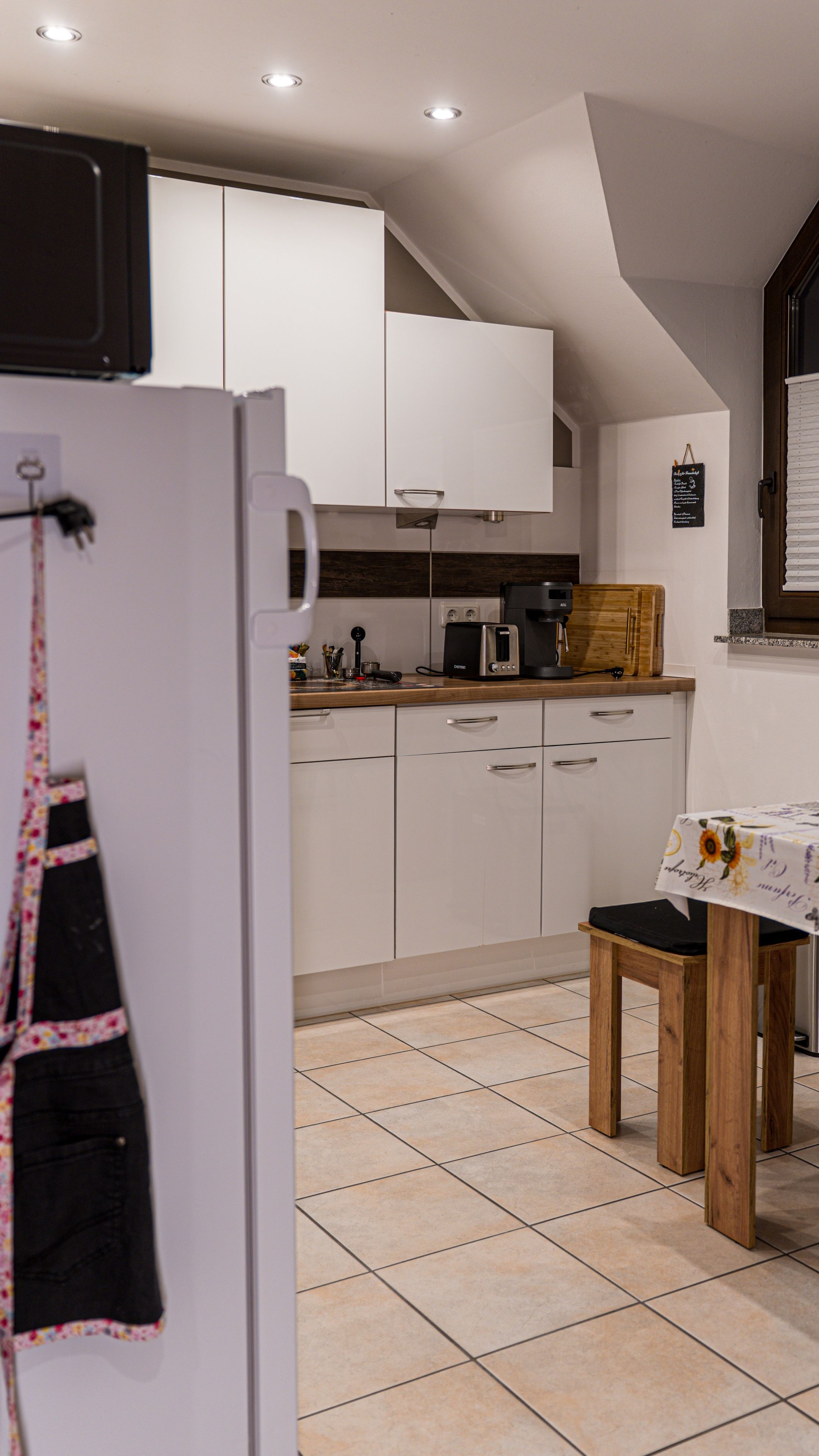 A kitchen with white cabinets, a wooden table, and a hanging apron.