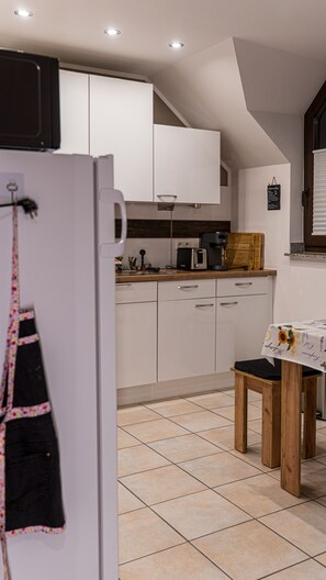 Een keuken met witte kastjes, een houten tafel en een ophangbaar schort.