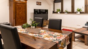 A dining area with a wooden table, chairs, and a floral tablecloth.