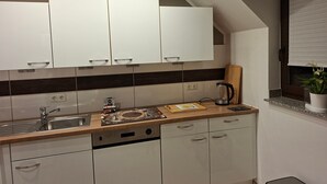 A modern kitchen with white cabinets, a stainless steel sink, and a coffee maker.