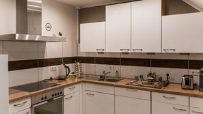 Una cocina moderna con armarios blancos, una campana extractora de acero inoxidable y un horno empotrado.