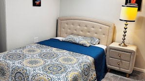 A bedroom with a bed, a nightstand, a lamp, and two wall art pieces. - Cozy room in delightful Wilmington home, close to all local attractions (Wilmington)