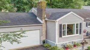 A single-story house with a garage, a chimney, and a small front yard with potted plants. - Cozy room in delightful Wilmington home, close to all local attractions (Wilmington)