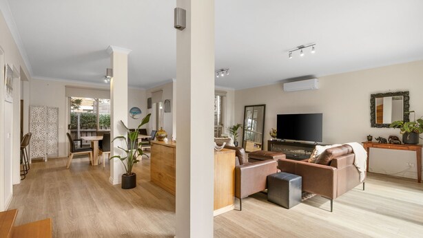 A spacious living area with a wooden floor, a sofa set, a TV, and a dining area with a table and chairs. - Fair Haven in Cape Woolamai (Cape Woolamai)