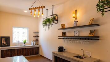 A modern kitchen with a built-in island, wooden cabinets, a coffee machine, and a hanging plant.