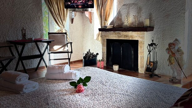 A cozy room with a fireplace, a television, and a bed with a decorative rose. - Δωμάτια Εξοχή-With fireplace and view to the sea (Diakopto)