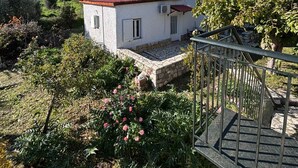 A small white building with a red roof, surrounded by lush greenery and a clear blue sky. - Δωμάτια Εξοχή-With fireplace and view to the sea (Diakopto)