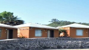 A row of single-story buildings with a stone wall in the foreground. - Mantra Resort Pvt Ltd (Bhor)